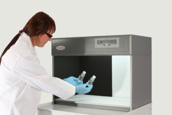 woman holding bottles in particulate colour assessment cabinet