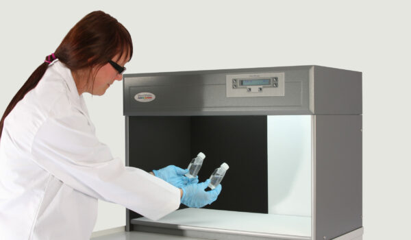 woman holding bottles in particulate colour assessment cabinet