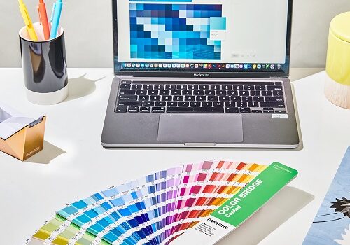 Pantone book and laptop on desk