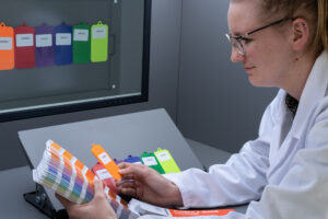 Scientist in white coat checking colours against Pantone book in VisionView