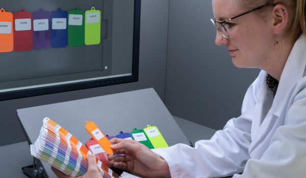 Scientist in white coat checking colours against Pantone book in VisionView