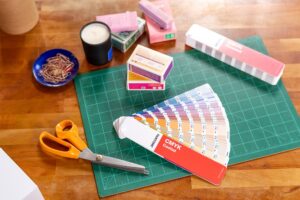 Pantone GP5101C CMYK colour fans on a cutting board with scissors and coloured packaging