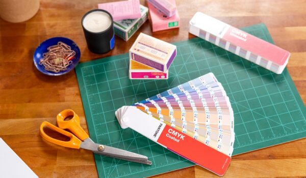 Pantone GP5101C CMYK colour fans on a cutting board with scissors and coloured packaging