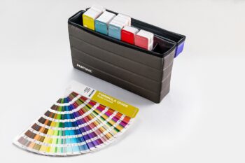 Pantone GPG301C Essential Guide Set case of colour guides open with one guide fanned out on desk